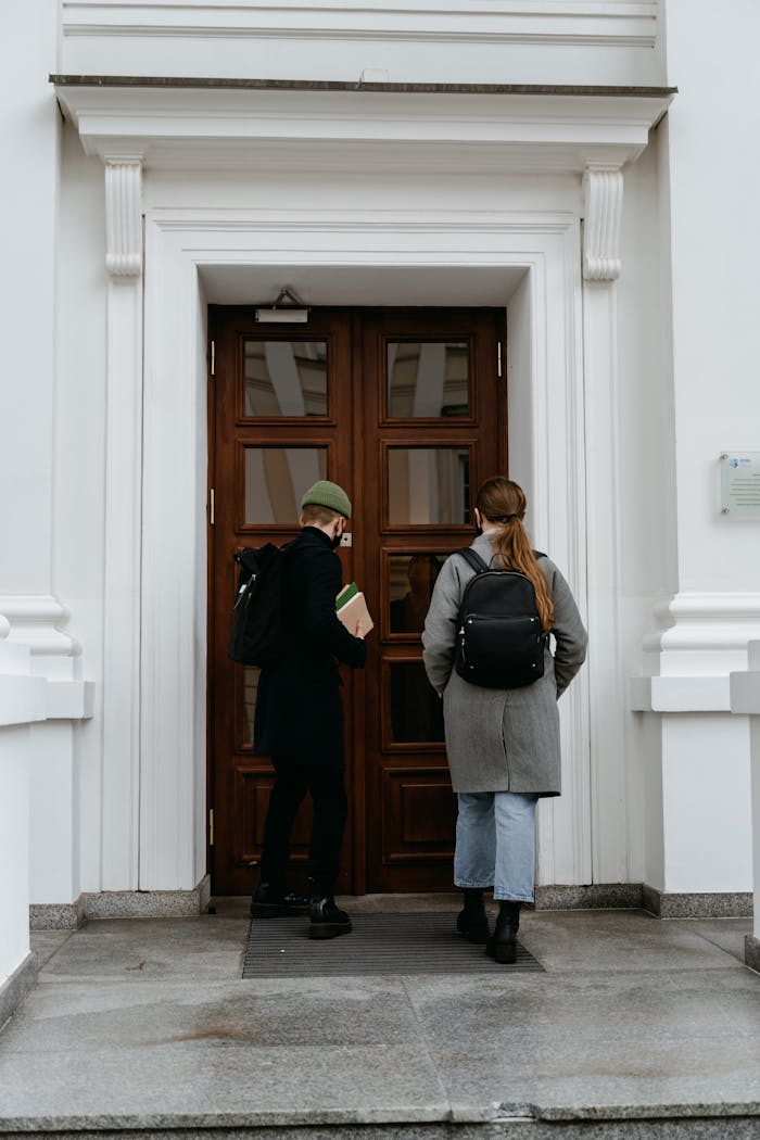 services-img Two students with backpacks entering a building through a wooden door