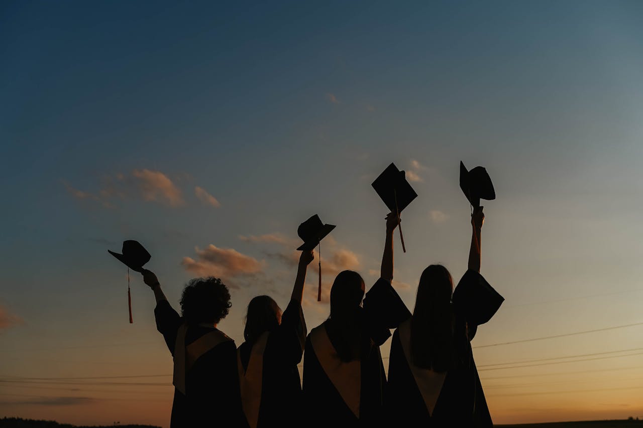 services-02 A group of graduates celebrate by raising their caps against a vibrant sunset sky, symbolizing achievement.